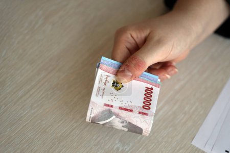 Mujer contable mano dar manojo de muchas cuentas de dinero de rupia indonesia de la nueva serie de cerca