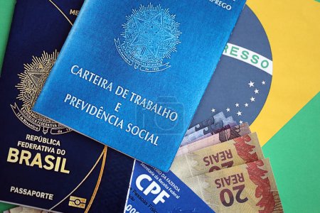 Reisepass Brasiliens, CPF-Steuerkarte und Arbeitskarte mit brasilianischen Reais-Geldscheinen auf Fahnenhintergrund Nahaufnahme