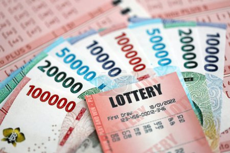 Rote Lotterielose liegen auf rosa Glücksspielblättern mit indonesischen Rupiah-Geldscheinen. Lotteriespielkonzept oder Spielsucht in Indonesien