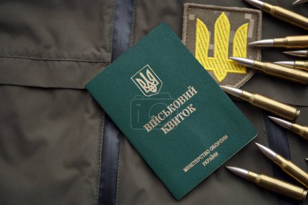 Military token or army ID ticket lies on green ukrainian military uniform indoors close up