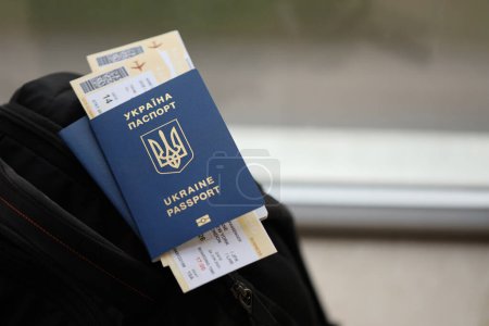 Deux passeports biométriques ukrainiens avec billets d'avion sur sac à dos touristique noir de près