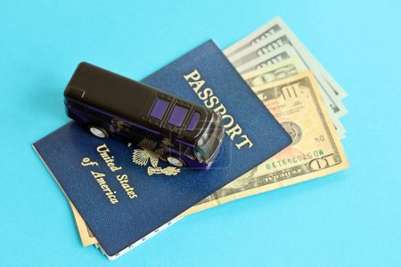Blue United States of America passport with money and toy bus on blue background close up. Tourism and travel concept
