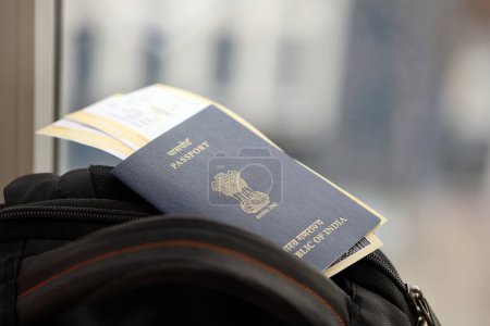 Pasaporte indio azul con billetes de avión en mochila turística de cerca. Concepto de turismo y viajes