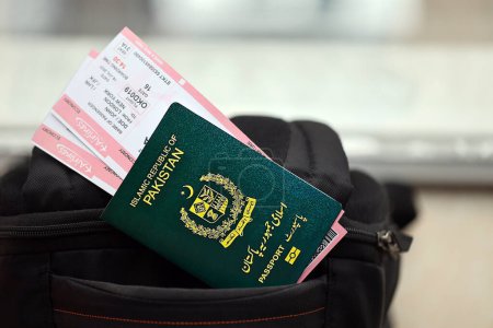 Pasaporte de la República Islámica Verde de Pakistán con pasajes aéreos en mochila turística de cerca. Concepto de turismo y viajes