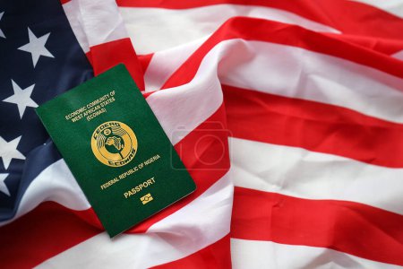 Green Nigerian passport on United States national flag background close up. Tourism and diplomacy concept