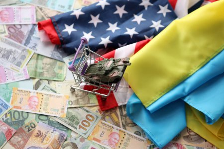 Tanque de juguete en bandera estadounidense y bandera ucraniana en muchos billetes de diferentes monedas. Antecedentes de financiación de la guerra y apoyo militar entre Estados Unidos y Ucrania