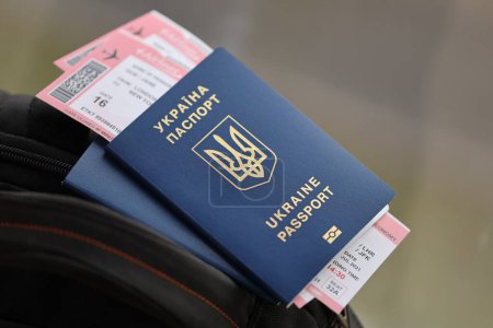Zwei ukrainische biometrische Pässe mit Flugtickets auf schwarzem Touristenrucksack in Großaufnahme