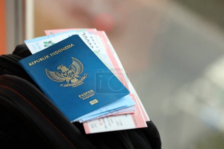 Téléchargez les photos : Blue Republic Indonesia passeport avec de l'argent et des billets d'avion sur le sac à dos touristique fermer. Tourisme et concept de voyage - en image libre de droit