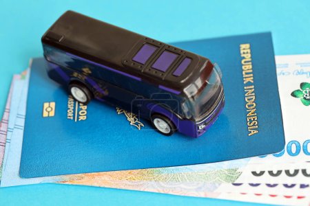 Blue Republic Indonesia passport with money and toy bus on blue background close up. Tourism and travel concept
