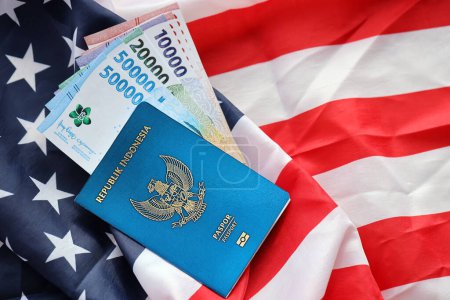 Foto de Pasaporte y dinero de la República Azul de Indonesia en el fondo de la bandera nacional de Estados Unidos de cerca. Concepto de turismo y diplomacia - Imagen libre de derechos