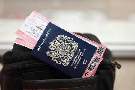 Pasaporte británico azul con billetes de avión en mochila turística de cerca. Concepto de turismo y viajes