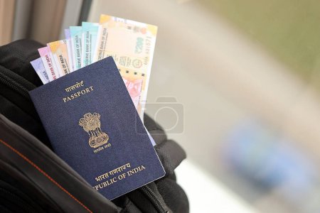 Blauer indischer Pass mit Geld und Flugtickets auf Touristenrucksack aus nächster Nähe. Tourismus- und Reisekonzept