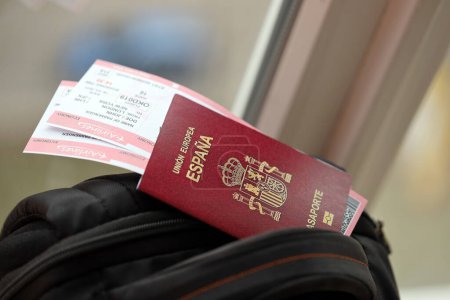 Pasaporte rojo español de la Unión Europea con billetes de avión en mochila turística de cerca. Concepto de turismo y viajes