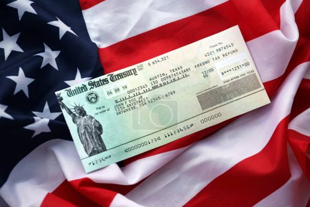Téléchargez les photos : États-Unis Trésor Vérifier le remboursement sur agitant drapeau américain de près. - en image libre de droit