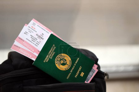 Grüner nigerianischer Pass mit Flugtickets auf Touristenrucksack in Großaufnahme. Tourismus- und Reisekonzept