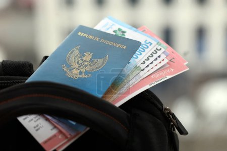 Téléchargez les photos : Blue Republic Indonesia passeport avec de l'argent et des billets d'avion sur le sac à dos touristique fermer. Tourisme et concept de voyage - en image libre de droit