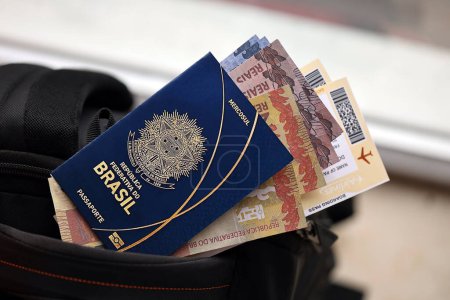 Passeport brésilien bleu avec de l'argent et des billets d'avion sur le sac à dos touristique de près. Tourisme et concept de voyage