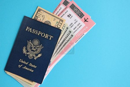 Passeport bleu des États-Unis d'Amérique avec de l'argent et des billets d'avion sur fond bleu de près. Tourisme et concept de voyage