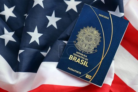Blauer brasilianischer Pass auf dem Hintergrund der US-Nationalflagge in Großaufnahme. Tourismus- und Diplomatie-Konzept