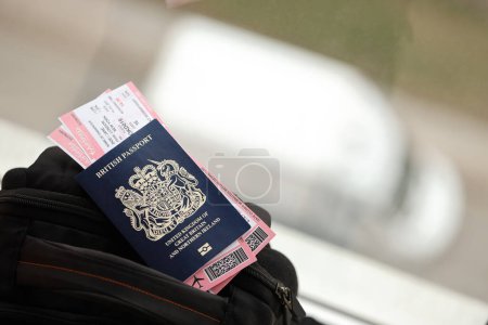 Blauer britischer Pass mit Flugtickets im Touristenrucksack aus nächster Nähe. Tourismus- und Reisekonzept