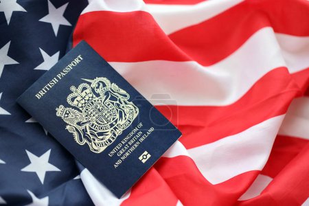 Blauer britischer Pass auf dem Hintergrund der US-Nationalflagge in Großaufnahme. Tourismus- und Diplomatie-Konzept