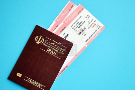 Red Islamic Republic of Iran passport with airline tickets on blue background close up. Tourism and travel concept
