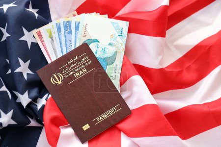 Red Islamic Republic of Iran passport and money on United States national flag background close up. Tourism and diplomacy concept