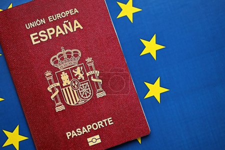 Pasaporte rojo español de la Unión Europea sobre fondo de bandera azul de cerca. Concepto de turismo y ciudadanía