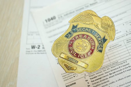 Foto de KYIV, UCRANIA - 9 de marzo de 2024 US Treasury Police Secret Service Officer badge on 1040 and W-2 IRS tax forms close up - Imagen libre de derechos