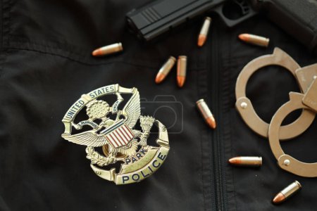 Téléchargez les photos : KYIV, UKRAINE - 9 MARS 2024 États-Unis United States Park Insigne de police en uniforme veste noire avec arme à feu, balles et menottes près - en image libre de droit