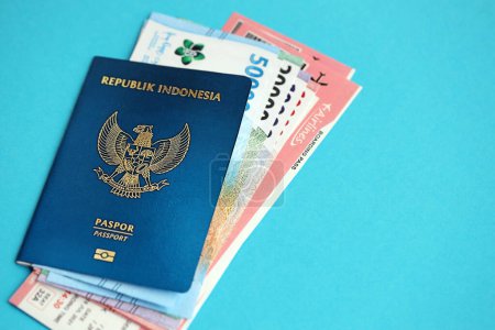 Téléchargez les photos : Blue Republic Indonesia passeport avec de l'argent et des billets d'avion sur fond bleu fermer. Tourisme et concept de voyage - en image libre de droit