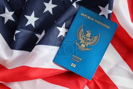 Der Pass der Blauen Republik Indonesien auf dem Hintergrund der Nationalflagge der Vereinigten Staaten in Großaufnahme. Tourismus- und Diplomatie-Konzept