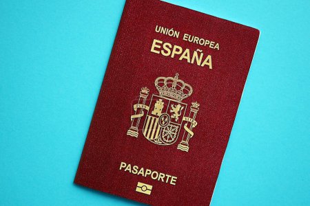 Red Spanish passport of European Union on blue background close up. Tourism and citizenship concept