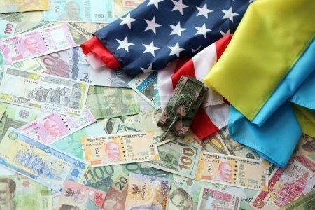 Téléchargez les photos : Réservoir de jouets sur le drapeau américain et le drapeau ukrainien sur de nombreux billets de différentes devises. Contexte du financement de la guerre et du soutien militaire entre les États-Unis et l'Ukraine - en image libre de droit