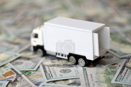 Delivery truck on hundred dollar bills banknotes. Background of moving or trucking concept close up