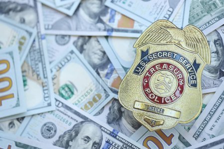 Foto de KYIV, UCRANIA - 9 de marzo de 2024 La insignia del oficial del Servicio Secreto de la Policía del Tesoro de los Estados Unidos en muchos billetes de cien dólares se cierra - Imagen libre de derechos