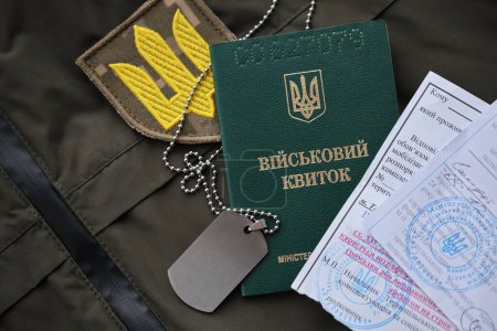 Téléchargez les photos : Jeton militaire ou billet d'identité de l'armée avec avis de mobilisation se trouve sur l'uniforme militaire ukrainien vert à l'intérieur fermer - en image libre de droit