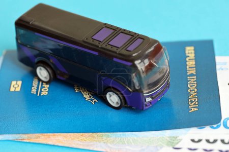 Blue Republic Indonesia passport with money and toy bus on blue background close up. Tourism and travel concept
