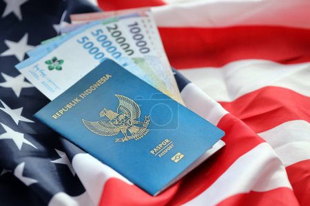 Blaue Republik Indonesien Pass und Geld auf dem Hintergrund der Nationalflagge der Vereinigten Staaten in Nahaufnahme. Tourismus- und Diplomatie-Konzept
