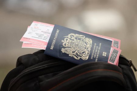 Blauer britischer Pass mit Flugtickets im Touristenrucksack aus nächster Nähe. Tourismus- und Reisekonzept
