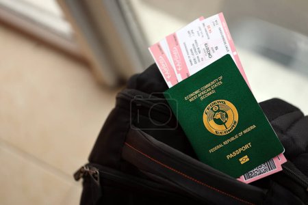 Grüner nigerianischer Pass mit Flugtickets auf Touristenrucksack in Großaufnahme. Tourismus- und Reisekonzept