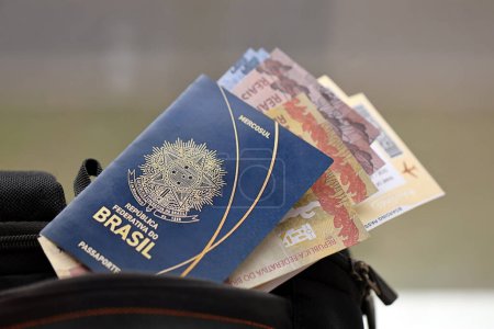 Pasaporte brasileño azul con billetes de avión y dinero en mochila turística de cerca. Concepto de turismo y viajes