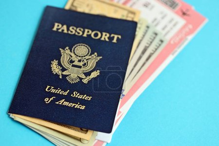Pasaporte azul de los Estados Unidos de América con billetes de avión y dinero en fondo azul de cerca. Concepto de turismo y viajes