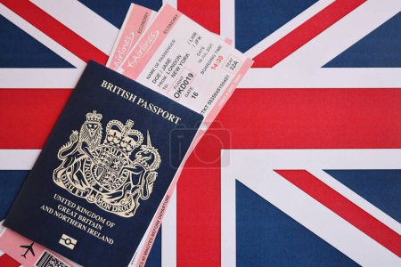 Pasaporte británico azul con billetes de avión en el fondo de la bandera nacional de cerca. Concepto de turismo y viajes