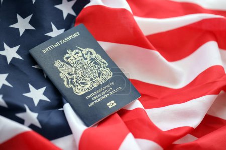 Blauer britischer Pass auf dem Hintergrund der US-Nationalflagge in Großaufnahme. Tourismus- und Diplomatie-Konzept