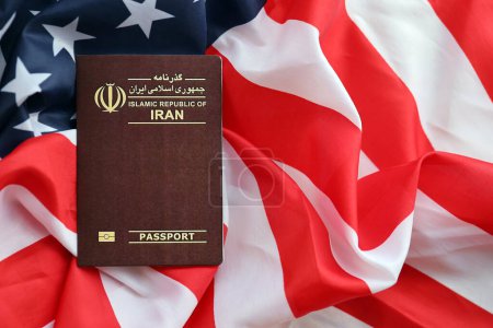 Passeport rouge de la République islamique d'Iran sur fond de drapeau national des États-Unis de près. Tourisme et diplomatie concept