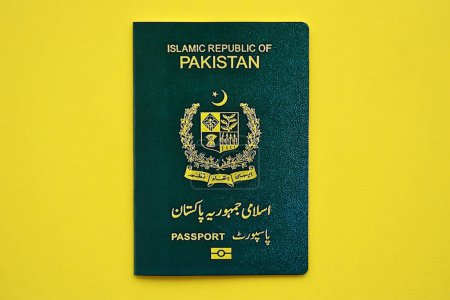 Green Islamic Republic of Pakistan passport on yellow background close up. Tourism and citizenship concept