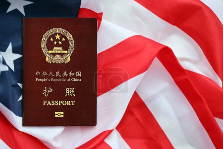 Red passport of People Republic of China on United States flag. PRC chinese passport on bright background close up