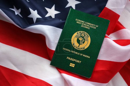Green Nigerian passport on United States national flag background close up. Tourism and diplomacy concept
