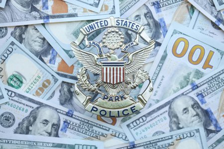 Foto de KYIV, UCRANIA - 9 de marzo de 2024 US United States Park Police badge on many US hundred dollar bills close up - Imagen libre de derechos